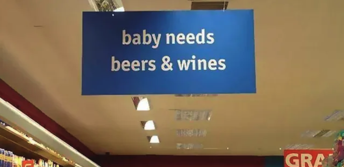 Ceiling-mounted sign in a supermarket "baby needs / beers & wines"